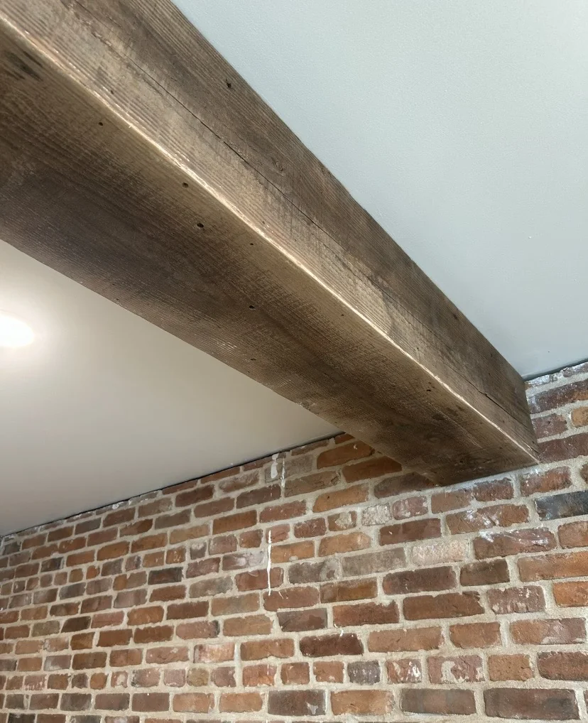 Wood ceiling beams beside an exposed-brick feature wall